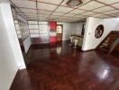 Spacious living area with wooden flooring, leading to kitchen and stairway