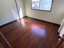 Empty bedroom with window and wooden floors