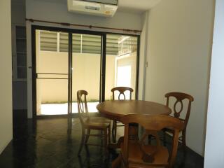 Dining area with a round wooden table and chairs in front of sliding glass doors