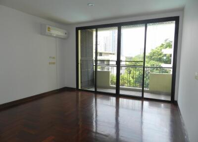 Spacious living room with wooden flooring and large glass doors leading to a balcony