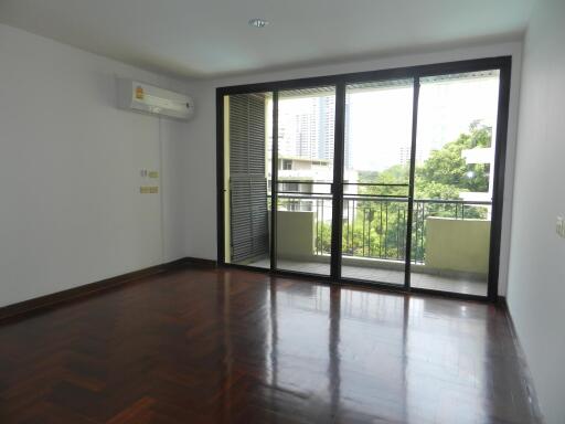 Spacious living room with wooden flooring and large glass doors leading to a balcony