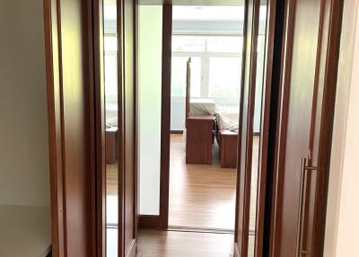 Well-lit hallway with wooden flooring and built-in closets