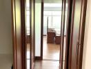 Well-lit hallway with wooden flooring and built-in closets