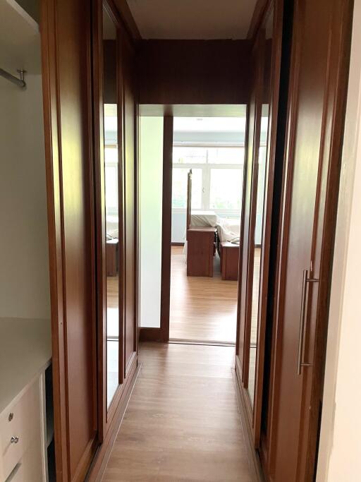 Well-lit hallway with wooden flooring and built-in closets