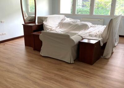 Bedroom with furniture covered by white sheets and a large window