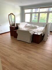 Bedroom with furniture covered by white sheets and a large window