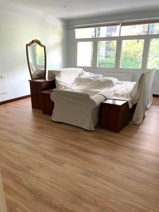 Bedroom with furniture covered by white sheets and a large window