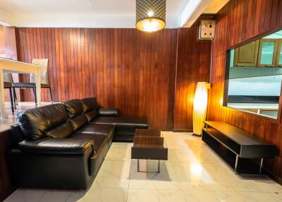 Cozy living room with wooden panel walls and black leather furniture