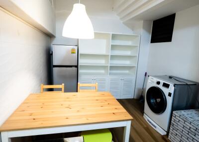 Small kitchen with dining table, fridge, and laundry machine