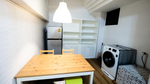 Small kitchen with dining table, fridge, and laundry machine