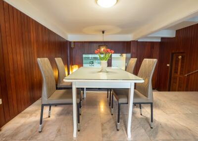 Elegant dining area with a modern table and six high-back chairs, set against wooden walls.