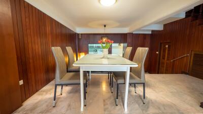 Elegant dining area with a modern table and six high-back chairs, set against wooden walls.