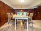 Elegant dining area with a modern table and six high-back chairs, set against wooden walls.