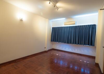 Spacious bedroom with hardwood floor, curtain, and air conditioner