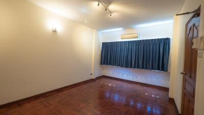 Spacious bedroom with hardwood floor, curtain, and air conditioner