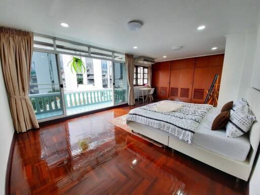 Spacious bedroom with balcony and hardwood floors