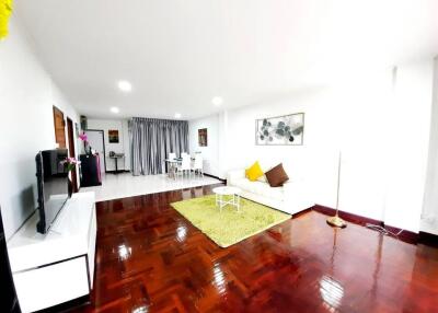 Spacious living room with white sofa, colorful cushions, and wooden flooring