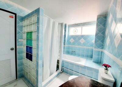 Modern blue-tiled bathroom with a bathtub and shower