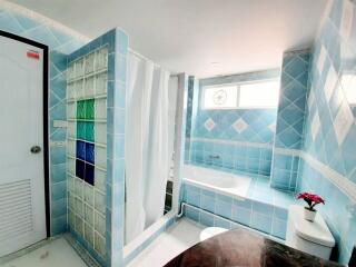 Modern blue-tiled bathroom with a bathtub and shower