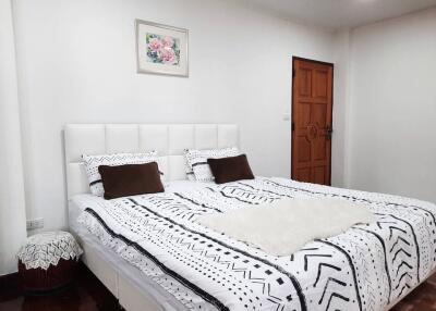 Spacious bedroom with a double bed, wooden door, and framed artwork