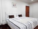 Spacious bedroom with a double bed, wooden door, and framed artwork