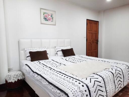 Spacious bedroom with a double bed, wooden door, and framed artwork