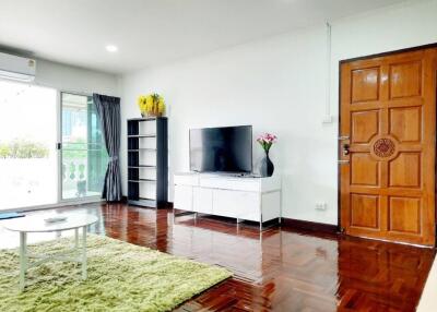 Modern living room with a TV, wooden flooring, and balcony access