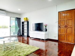 Modern living room with a TV, wooden flooring, and balcony access