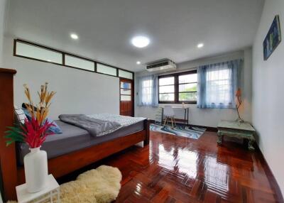 Spacious bedroom with polished wooden flooring, large windows, and modern furniture