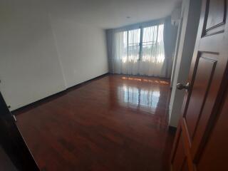 Empty bedroom with wooden floor and large window