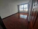 Empty bedroom with wooden floor and large window