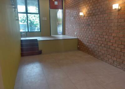 Living room area with brick wall, elevated platform, and large windows