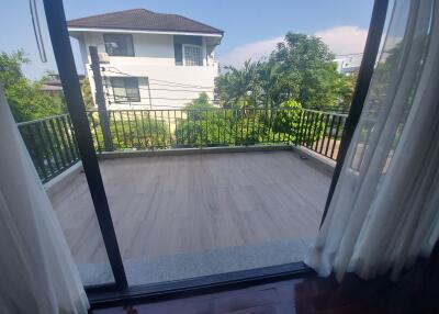 View of balcony from inside with curtains on sides and greenery outside