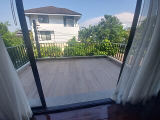 View of balcony from inside with curtains on sides and greenery outside