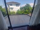 View of balcony from inside with curtains on sides and greenery outside