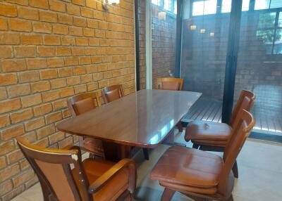 Dining room with brick walls and a wooden dining table surrounded by six chairs