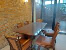 Dining room with brick walls and a wooden dining table surrounded by six chairs