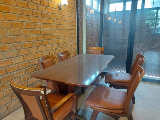 Dining room with brick walls and a wooden dining table surrounded by six chairs