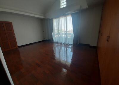 Spacious empty bedroom with polished wood floors and large window