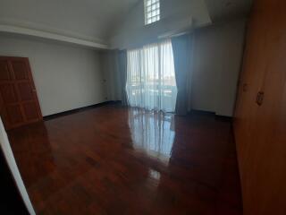 Spacious empty bedroom with polished wood floors and large window