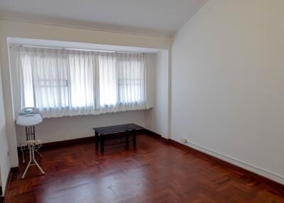 Spacious bedroom with wooden flooring and large window