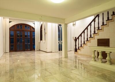 Spacious and elegant living room with polished floors, large windows, and a staircase