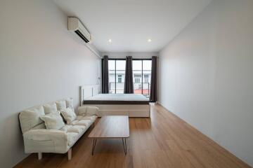 Minimalist bedroom with bed, sofa, and large windows