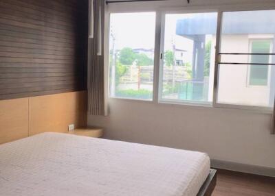 Modern bedroom with large window and wooden accent wall