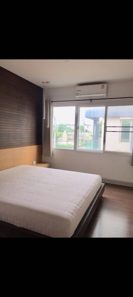 Modern bedroom with large window and wooden accent wall