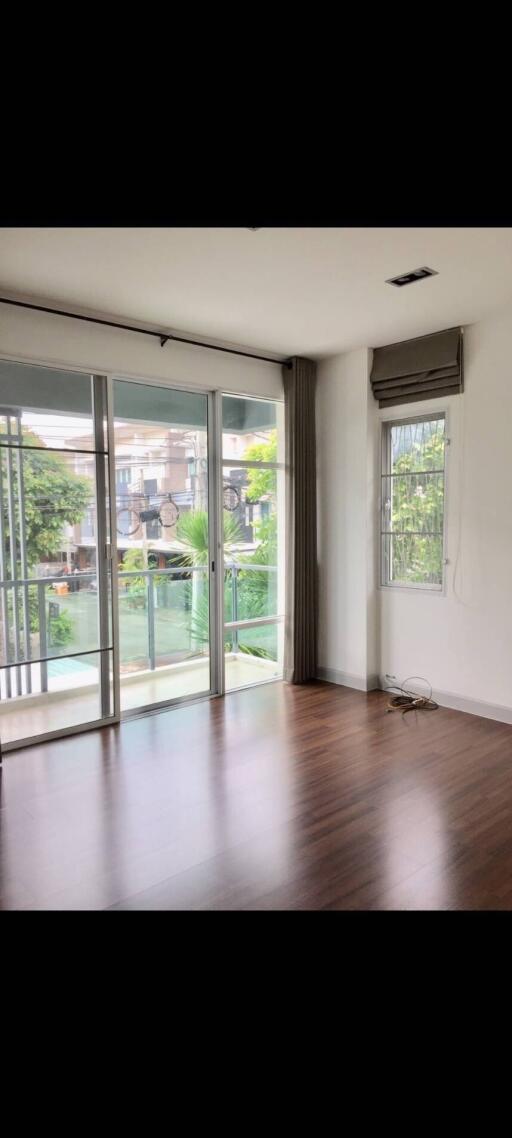 Spacious living room with hardwood floors, large windows, and balcony access