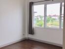 Empty bedroom with hardwood floors and large window