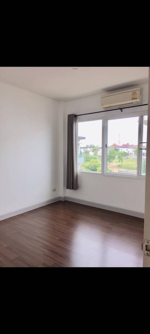 Empty bedroom with hardwood floors and large window