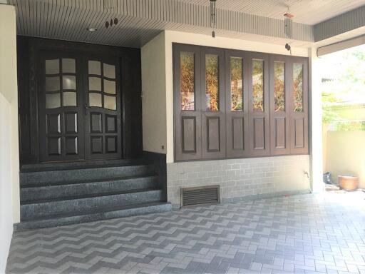 Main entrance with large dark wood doors and tiled steps