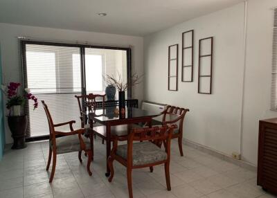 Dining area with wooden table and chairs, large windows, and decorative elements